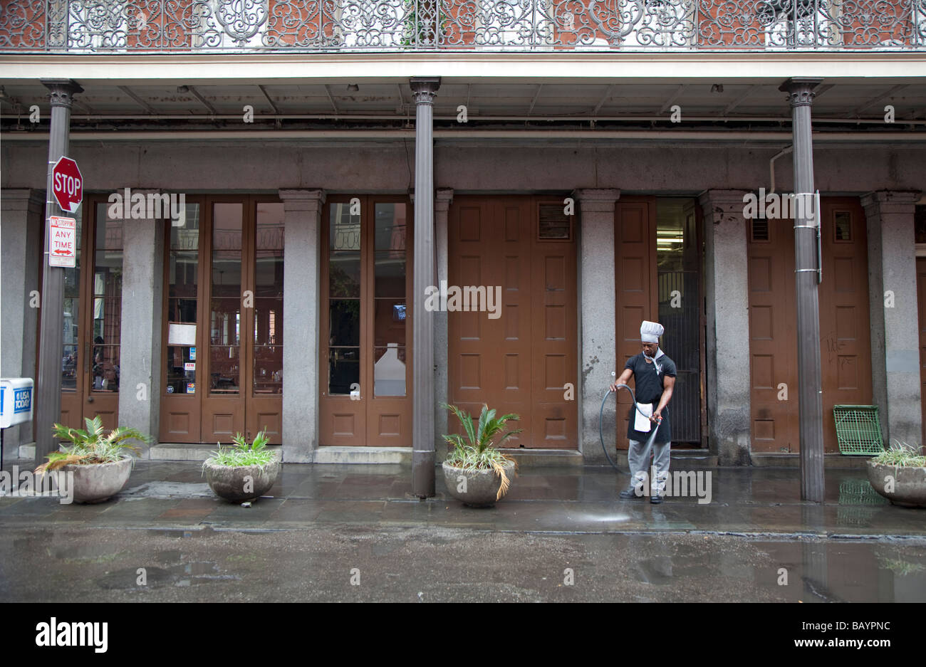 New Orleans in Louisiana un uomo che indossa un chef s hat pulisce il marciapiede al di fuori di un ristorante nel Quartiere Francese Foto Stock