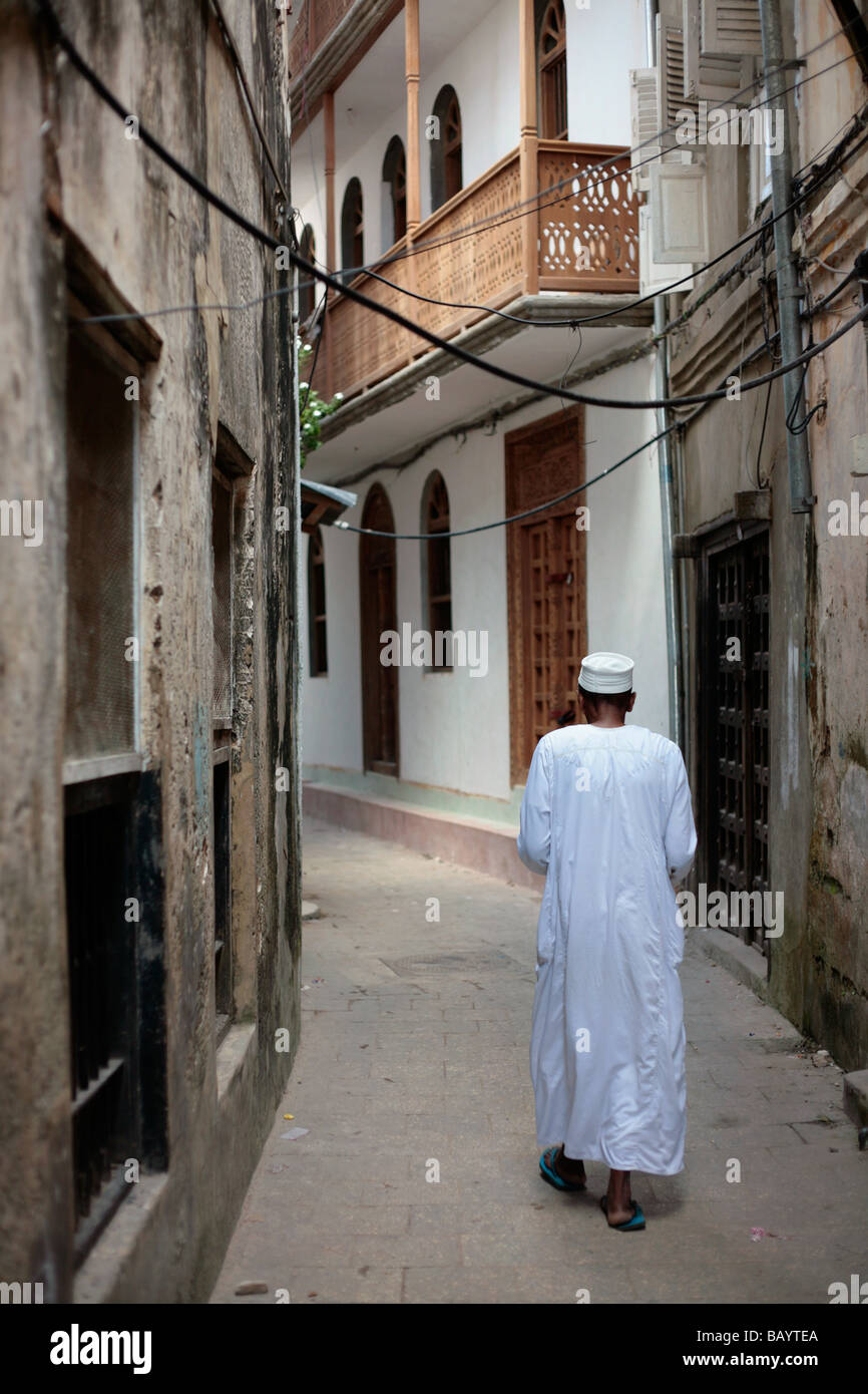 Ragazzo cammina in una stretta viuzza in Stone Town Zanzibar Foto Stock