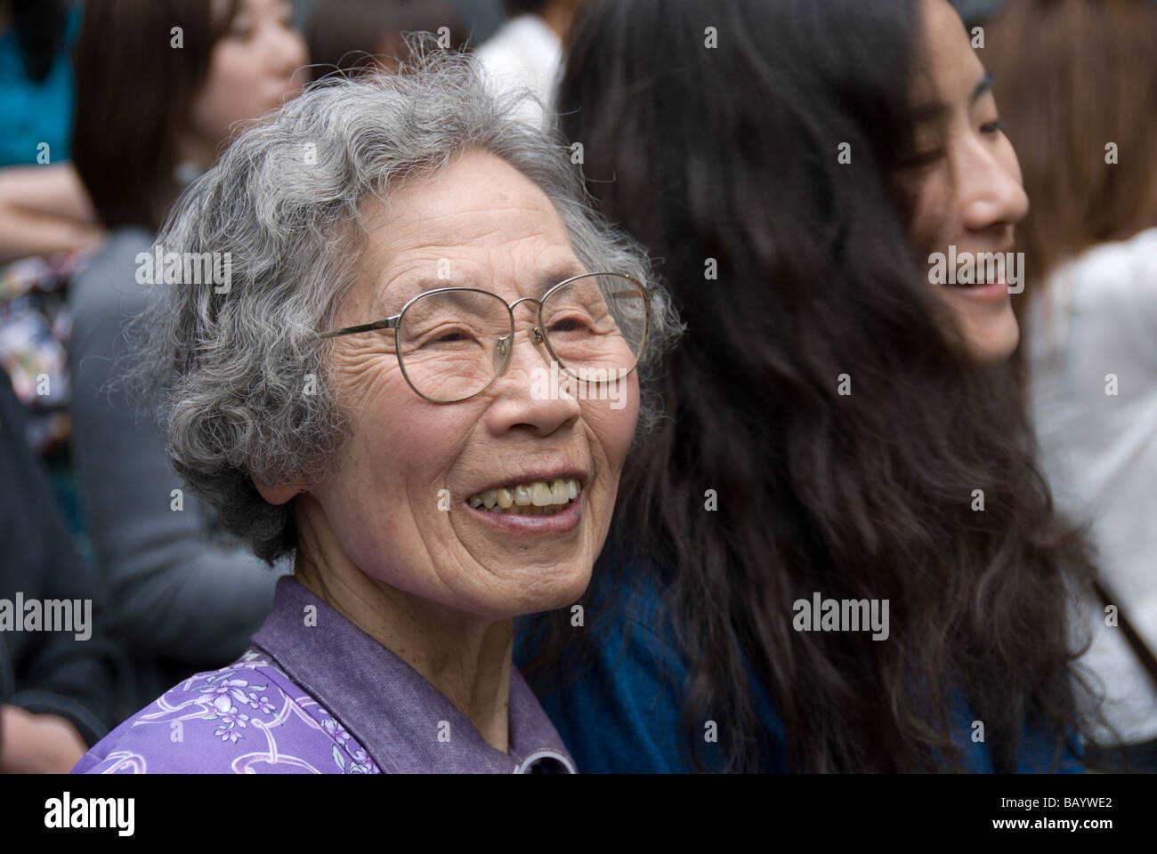 Una vecchia donna giapponese sorride accanto a una molto più giovane donna a un festival a Matsumoto, Giappone Foto Stock