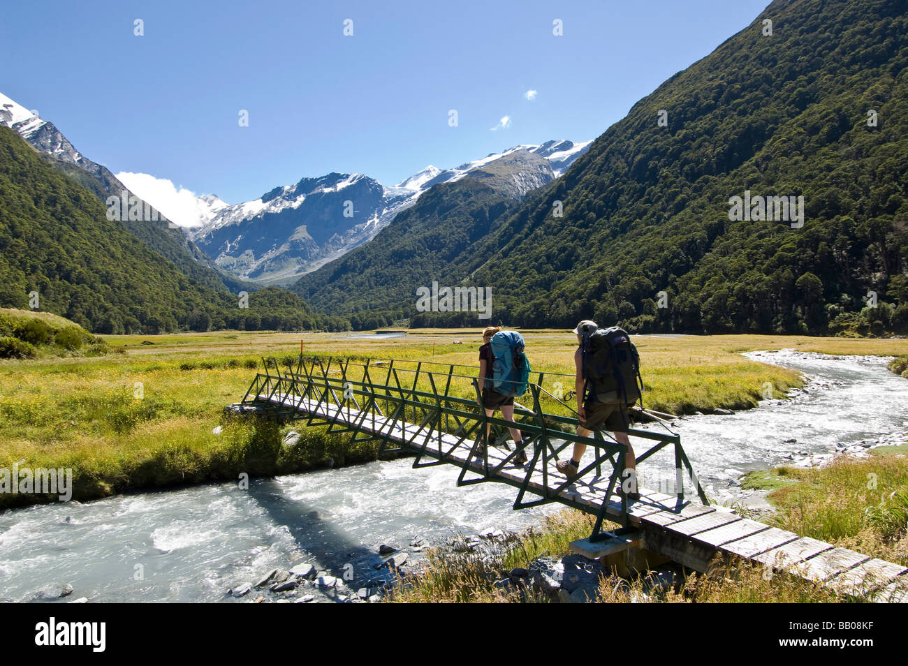 Gli escursionisti attraversando ponte in Occidente Matukituki River Valley Mount aspiranti Parco Nazionale dell'Isola del Sud della Nuova Zelanda Foto Stock