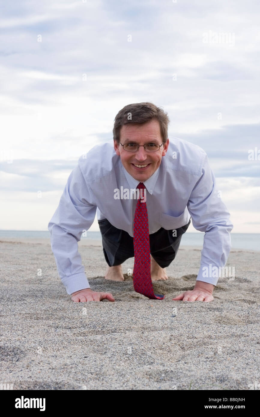 Imprenditore sorridente facendo spingere ups su una spiaggia Foto Stock