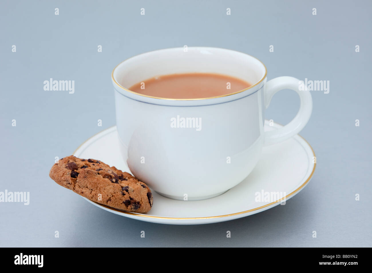 Una tazza di tè inglese e un piatto con un biscotto al cioccolato su uno sfondo semplice. Inghilterra Gran Bretagna Foto Stock