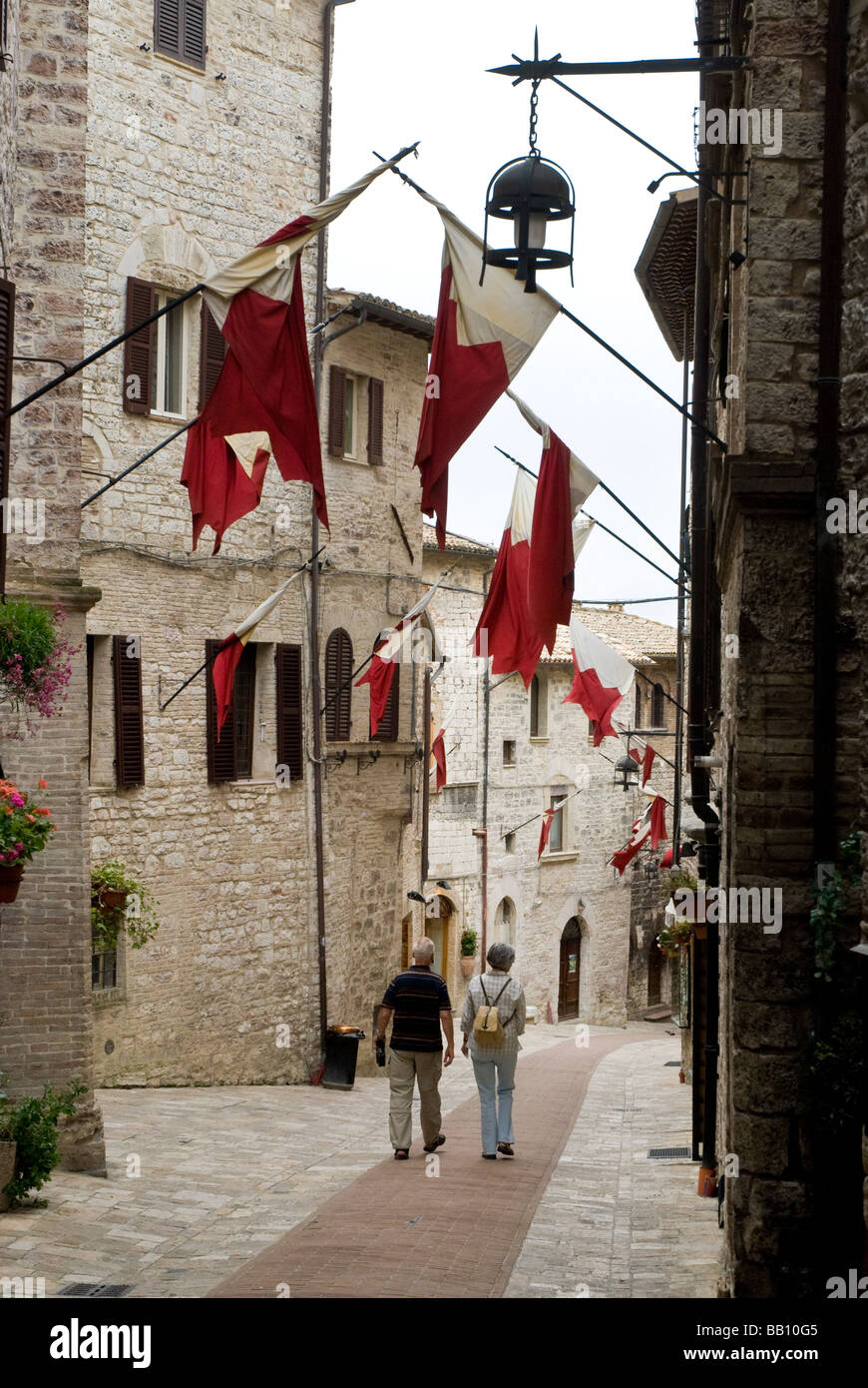 I turisti camminando per strada di bandiere in Assisi Foto Stock