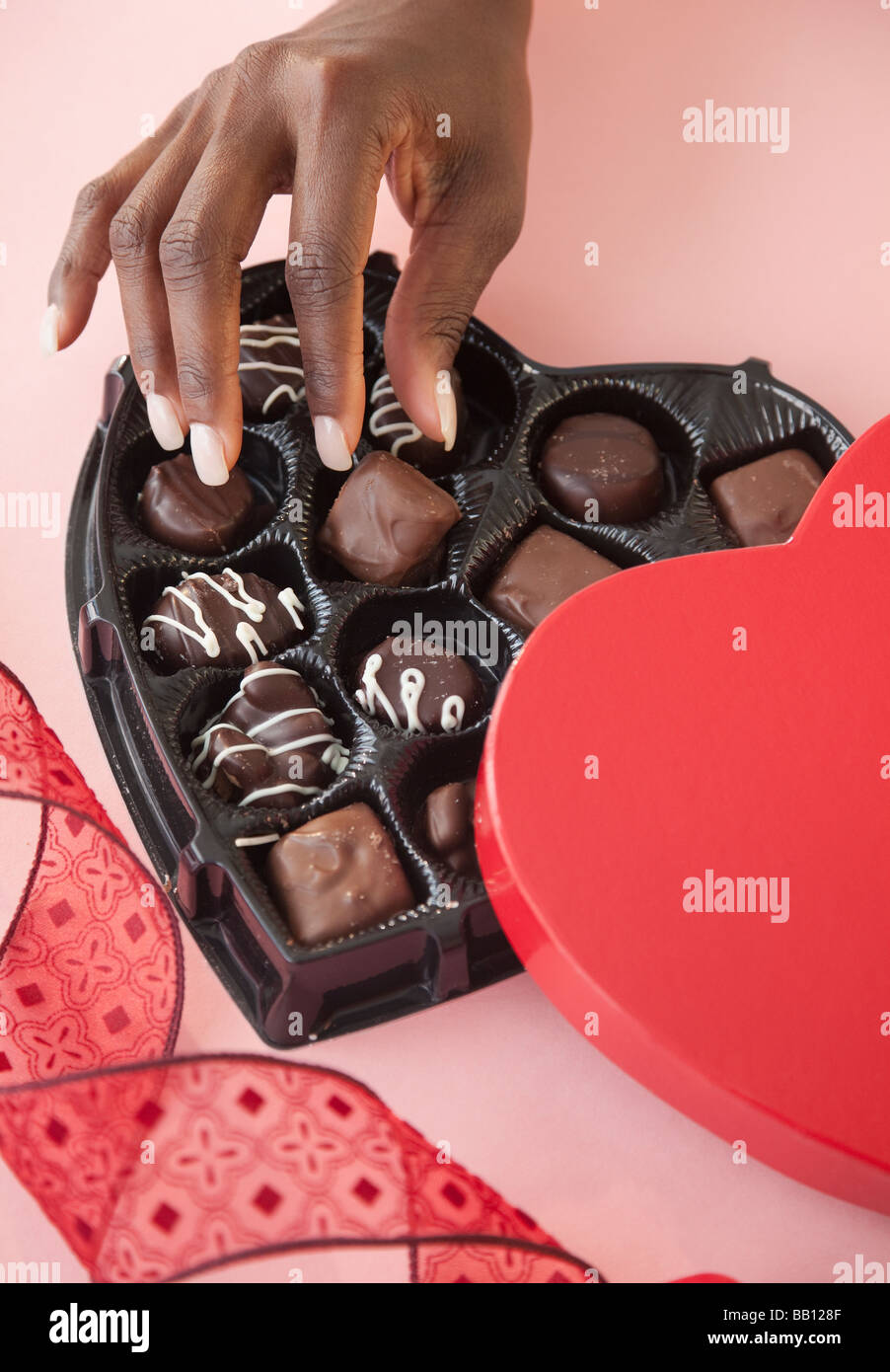 Donna africana prendendo i cioccolatini da casella di San Valentino Foto Stock