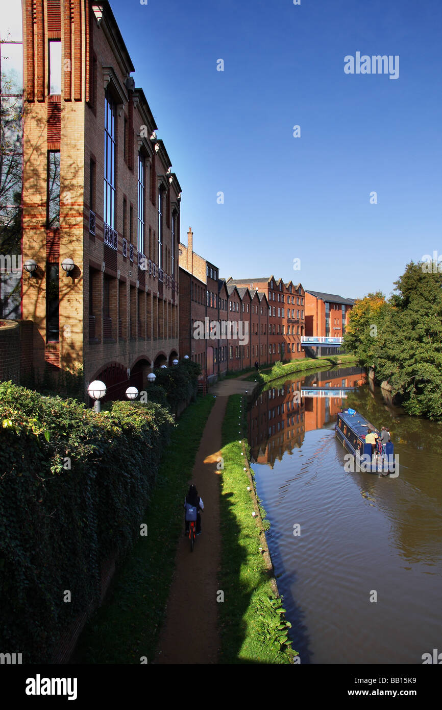 Uffici moderni accanto al fiume Wey nel centro di Guildford Surrey. Una stretta barca sul fiume e un ciclista sulla strada alzaia. Foto Stock