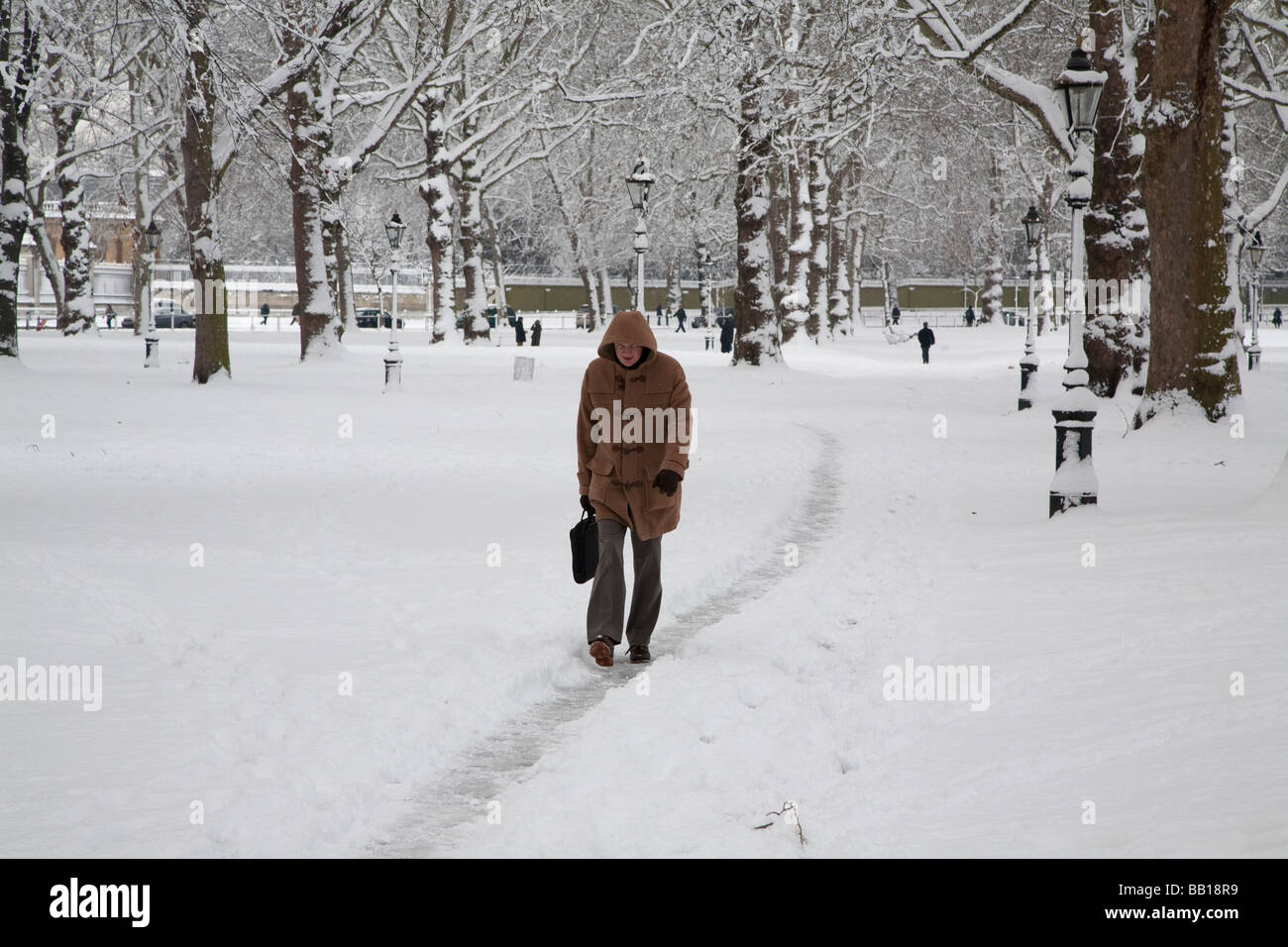 Uomo che cammina attraverso la coperta di neve park per arrivare al lavoro Foto Stock