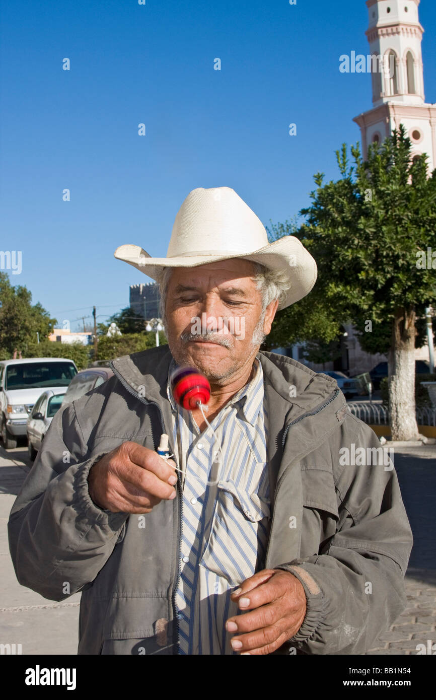 Uomo locale in El Fuerte, Messico, gioca con bambino giocattolo chiamato balero. Vi è una sfera su una stringa attaccato ad un bastone. Foto Stock
