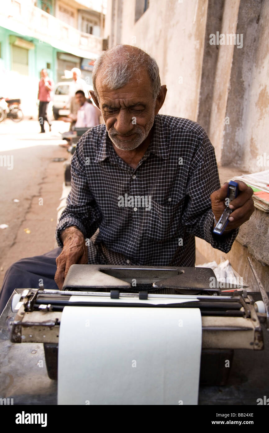 Un uomo si siede sulla strada lavorando su un typrewriter nel cuore della vecchia città di Ahmedabad, Gujarat. Foto Stock