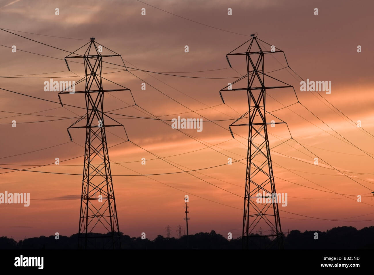 Le linee di alimentazione e la torre cellulare al tramonto Foto Stock