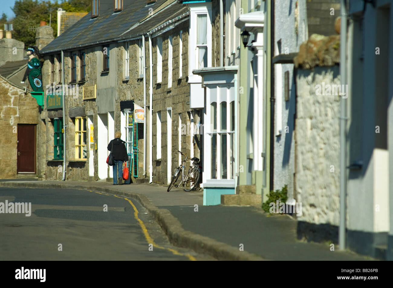 Strada di Hugh Town St Marys Isole Scilly con una persona che porta shopping bag Foto Stock