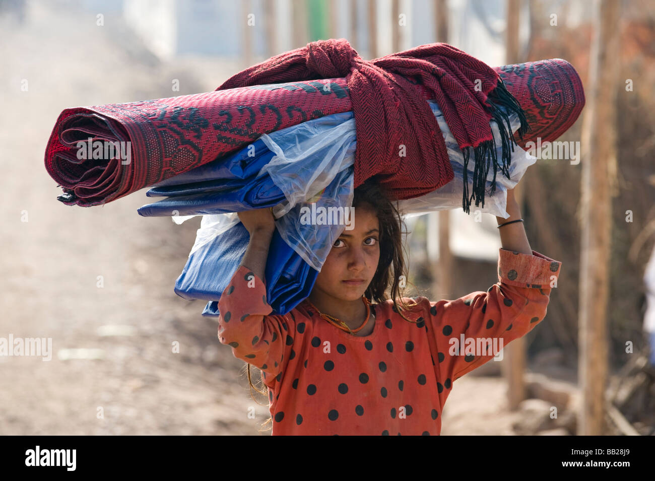 Una ragazza porta coperte dopo essere stato spostato dalla guerra in SWAT di Peshawar, Pakistan Foto Stock