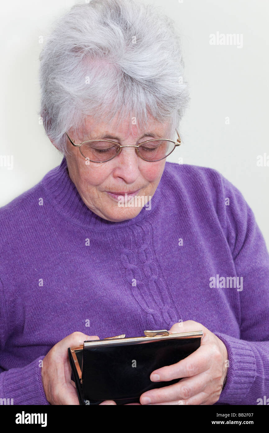 Close up di un squattrinati pensionato britannico cercando in un portamonete vuoto nelle sue mani con espressione in questione in tempi di austerità. Inghilterra Regno Unito Gran Bretagna Foto Stock