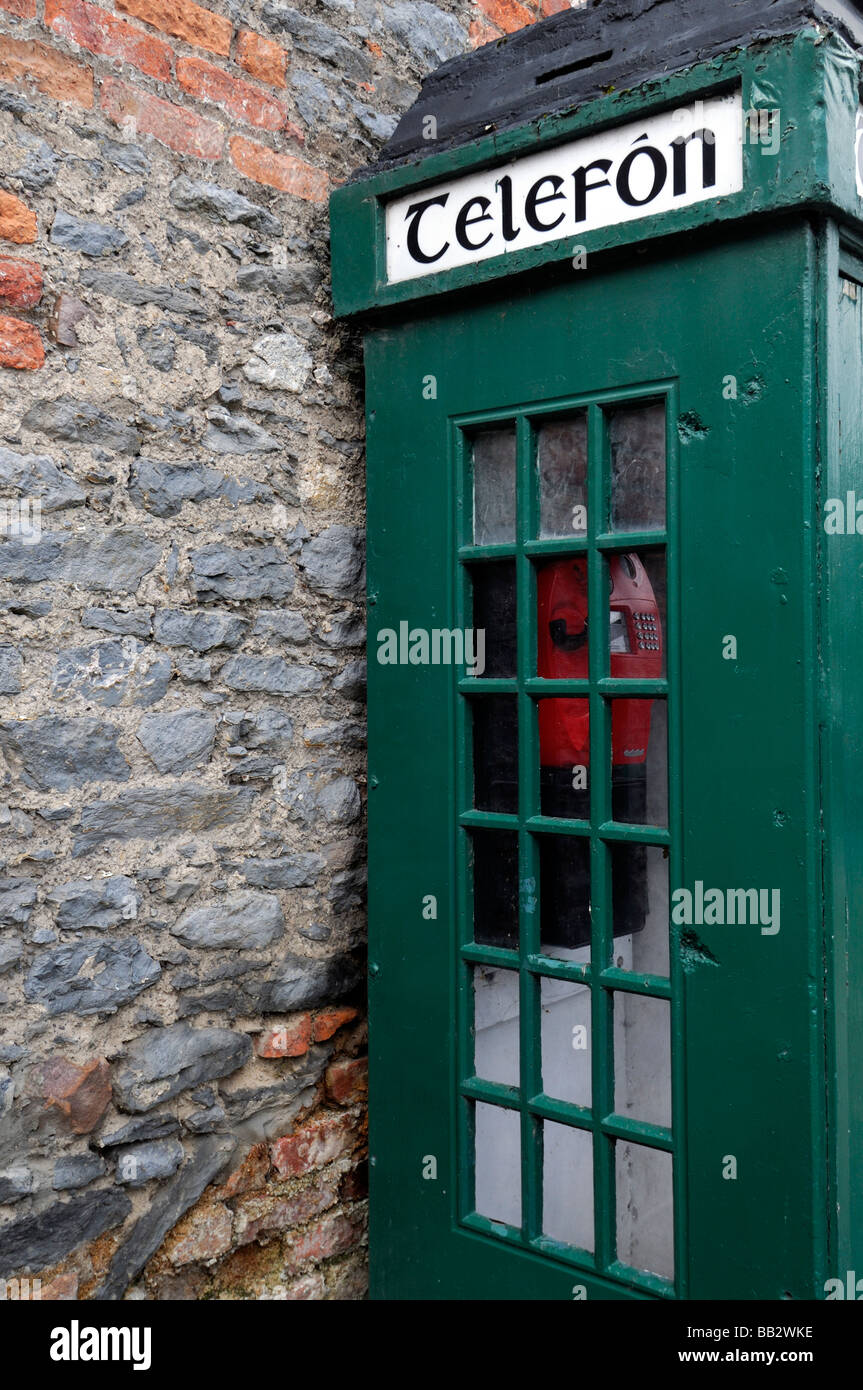Irlandese tradizionale telefono verde lato scatola rossa vista muro di mattoni vecchi inutilizzati disrepair in disuso la tecnologia obsoleta Foto Stock