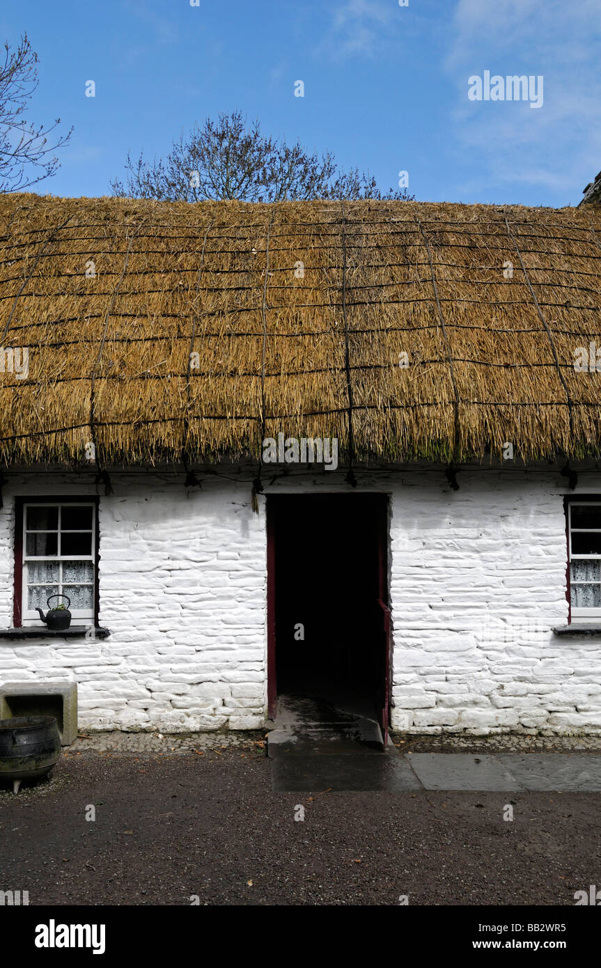 Tetto di Paglia cottage con mezza aperta porta in legno finestra bianca telaio verniciato bianco tradizionale casa di pietra blu cielo Irlanda Foto Stock