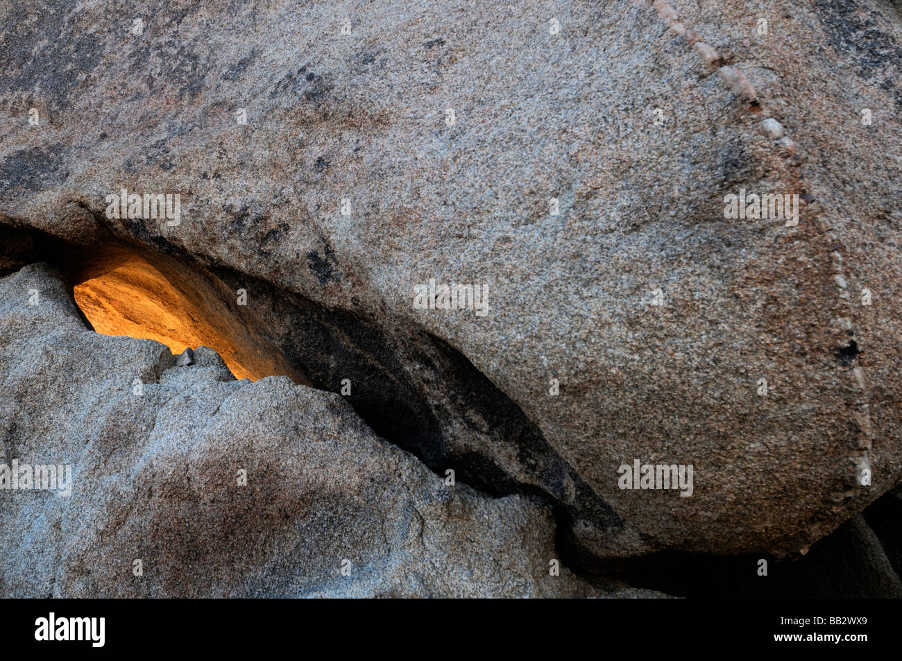 La luce del sole illumina brillare attraverso il crack formazione di roccia bianca area serbatoio Joshua Tree National Park California Foto Stock