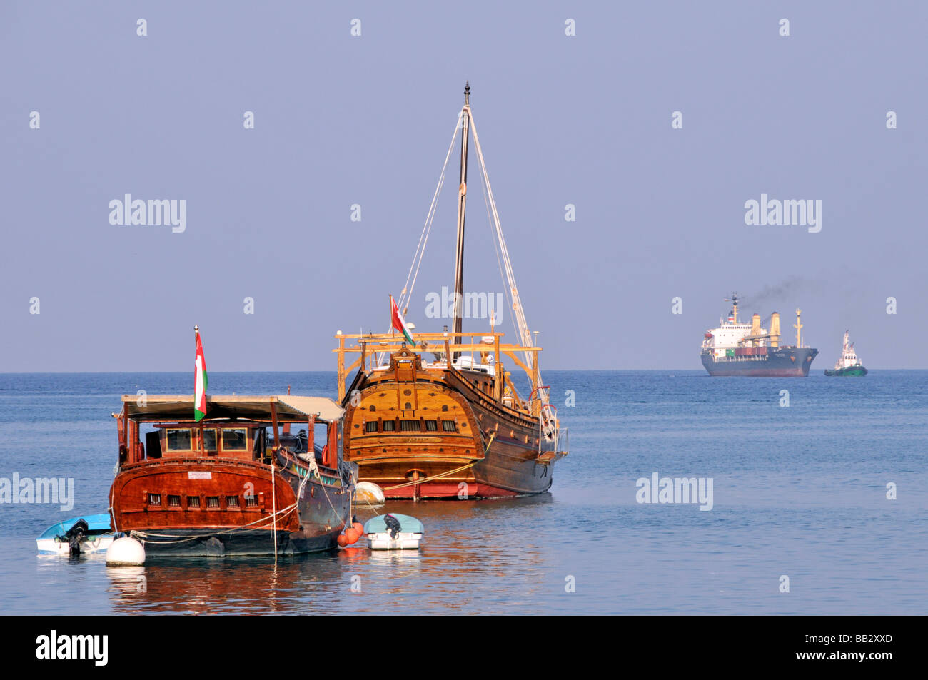 Antico e moderno trasporto a Port Sultan Qaboos Muscat Oman Dhows ormeggiato nel porto di Muttrah rimorchiatore nave container verso il porto Golfo di Oman Foto Stock