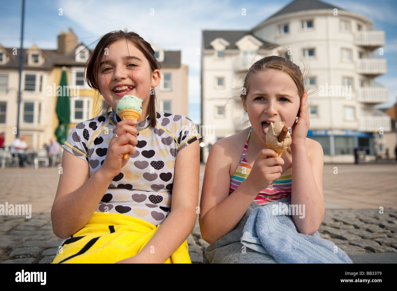 Due dieci anni di ragazze mangiando cornetti gelato al mare, in un pomeriggio d'estate, aberystwyth Wales UK Foto Stock