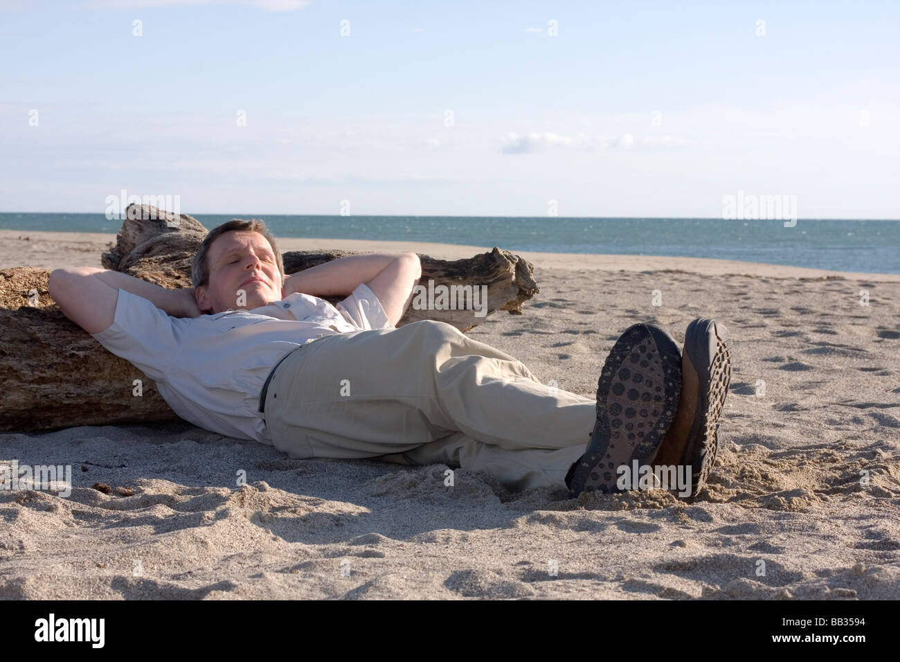 Uomo di dormire su una spiaggia in una giornata di sole Foto Stock