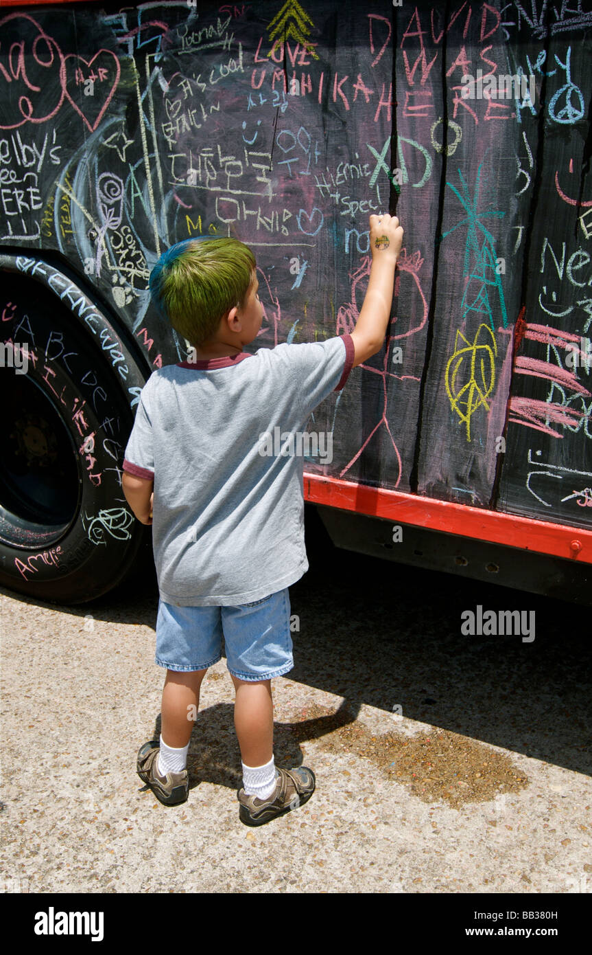 Ragazzo giovane scrive in gesso su arte auto in Houston parade Foto Stock