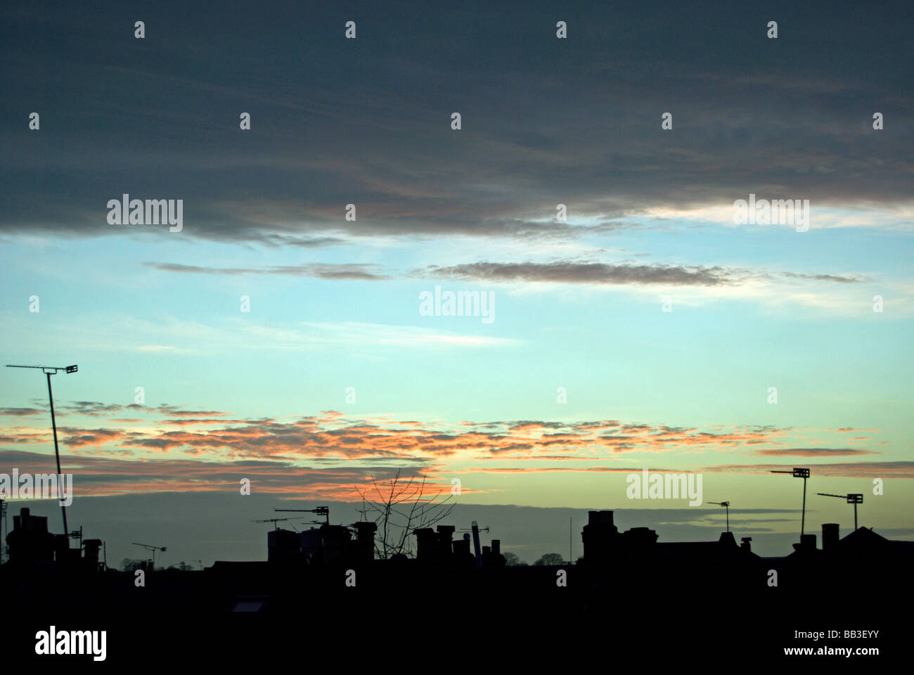 Vista su tetti urbano di parzialmente red sky con grande nube scura e il segmento di cielo blu chiaro Foto Stock