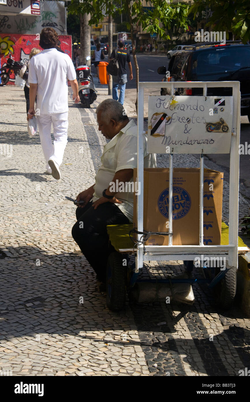 Un anziano tipi brasiliano di un messaggio di testo sul suo telefono cellulare su un marciapiede del quartiere di Copacabana, Rio de Janeiro, Brasile. Foto Stock