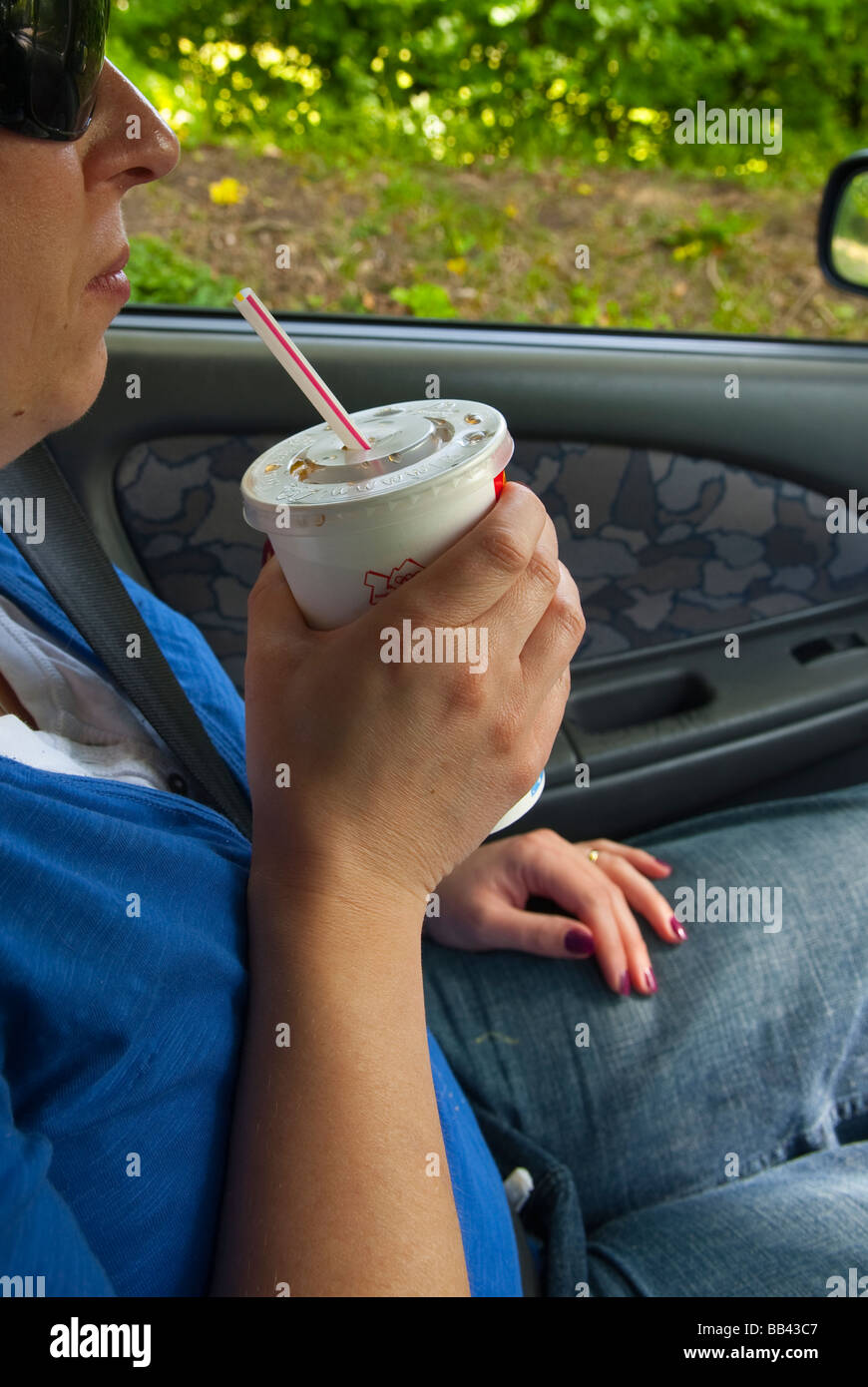 Una donna bere un mcdonalds coke con una cannuccia all'interno di una vettura nel Regno Unito Foto Stock