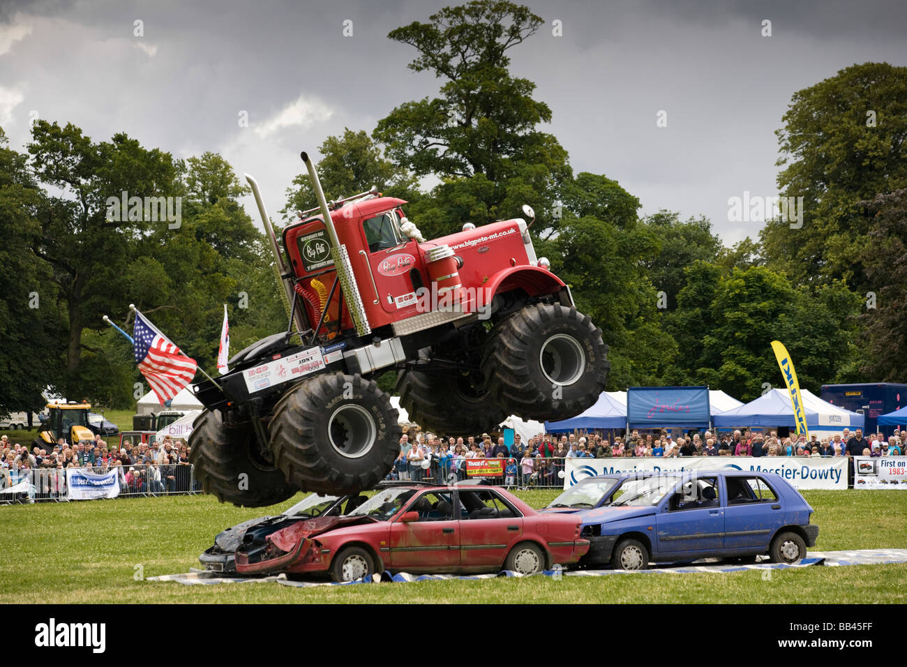 Monster Trucks la frantumazione di vecchie automobili in una farm show, Gloucestershire, Regno Unito Foto Stock