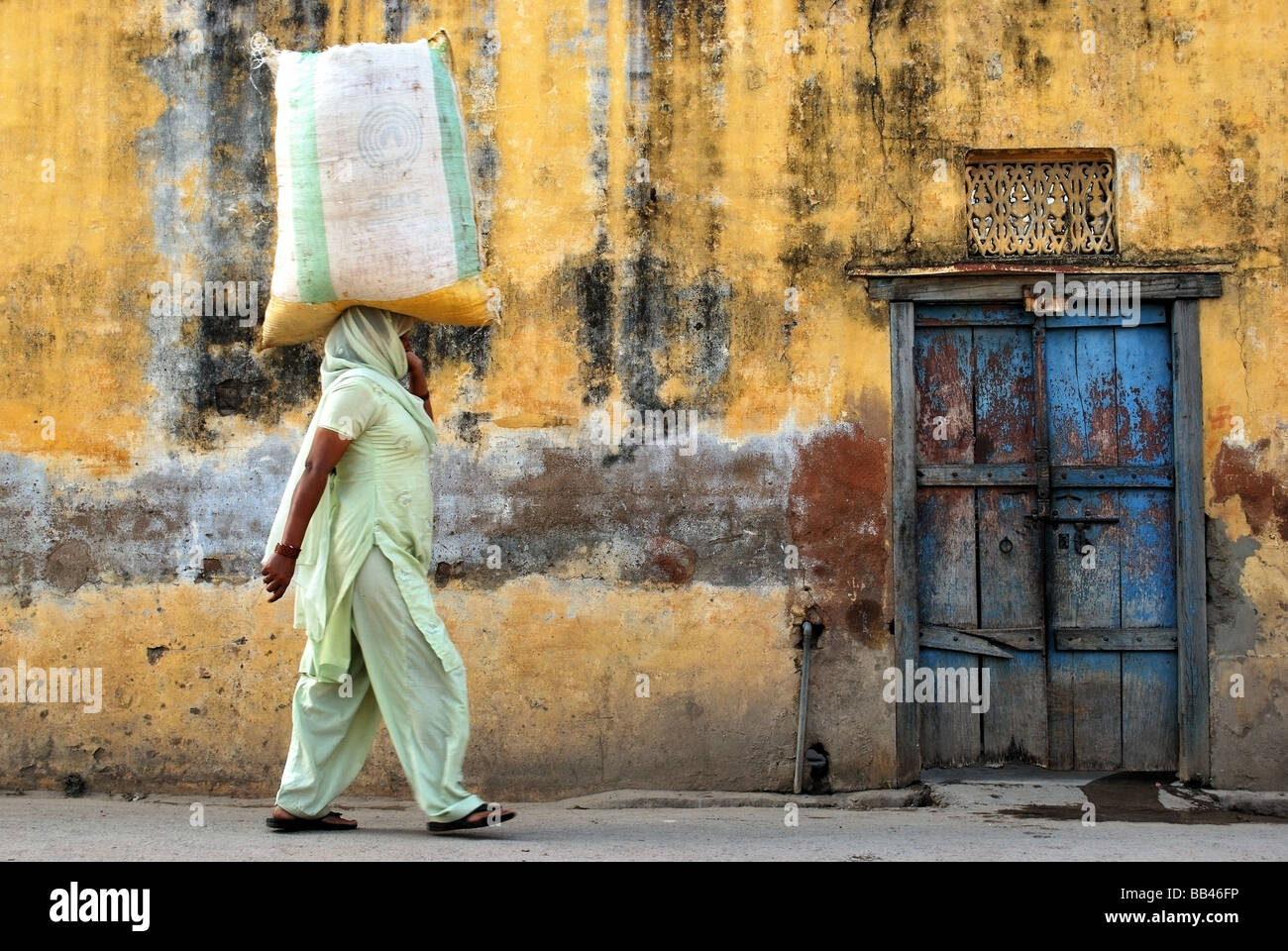 Scena colorati da Delhi con la donna borsa da trasporto sul suo capo Foto Stock