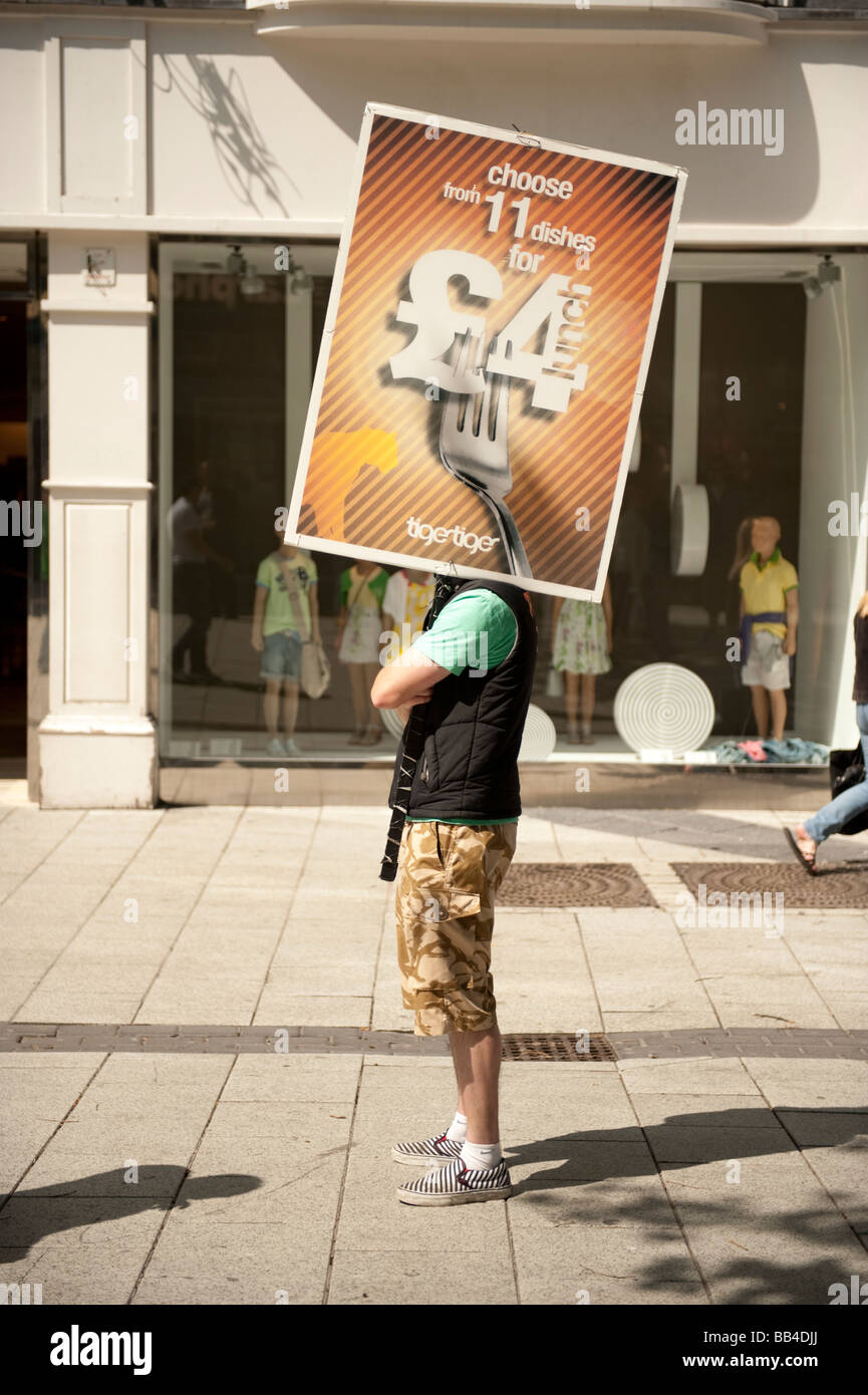 L'uomo impiegato sul salario minimo per tenere un banner pubblicitario nella street Cardiff City Centre Wales UK Foto Stock