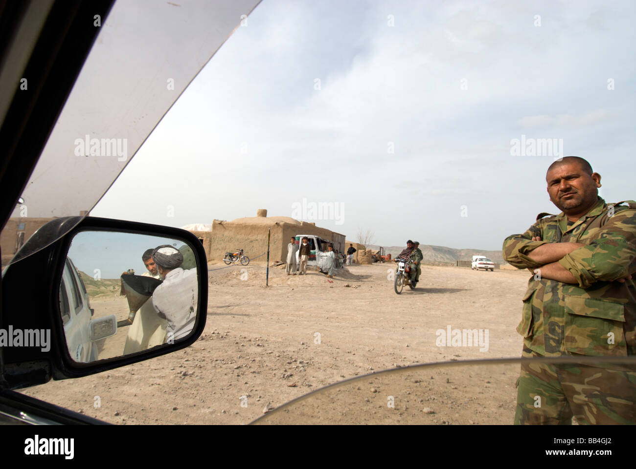 Una guardia di polizia si erge a un checkpoint mentre automobilista refuels, nel villaggio di Kareyze-e Elias, vicino al confine Afghan-Iran, H Foto Stock