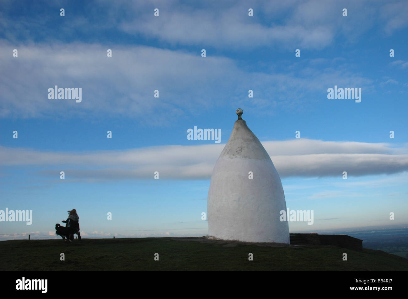Cielo drammatico su bianco Nancy, un punto di riferimento vicino a Macclesfield con la silhouette di una ragazza e il suo cane Foto Stock