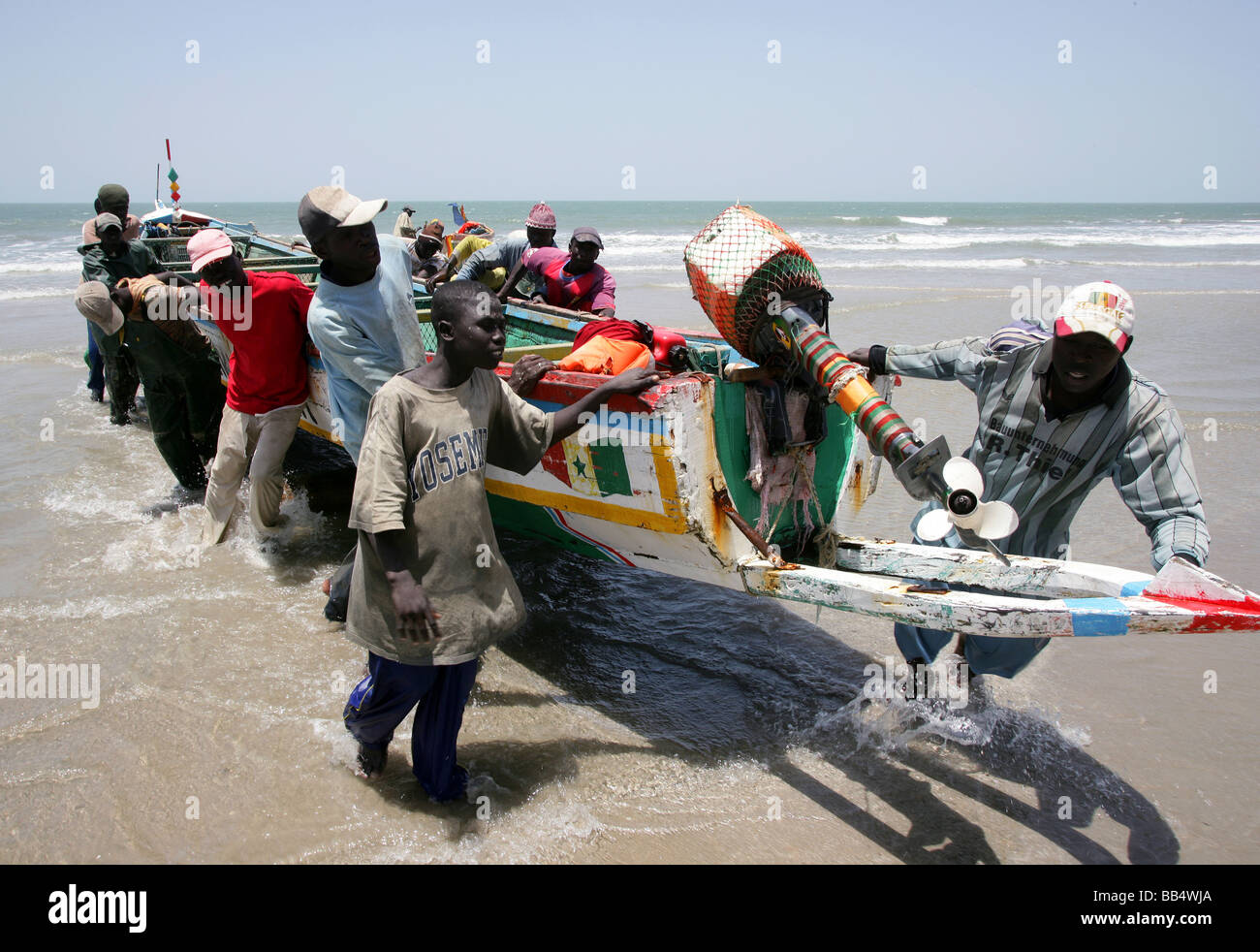 I pescatori di portare una barca fino sulla riva a Kap Skirring, Senegal Foto Stock