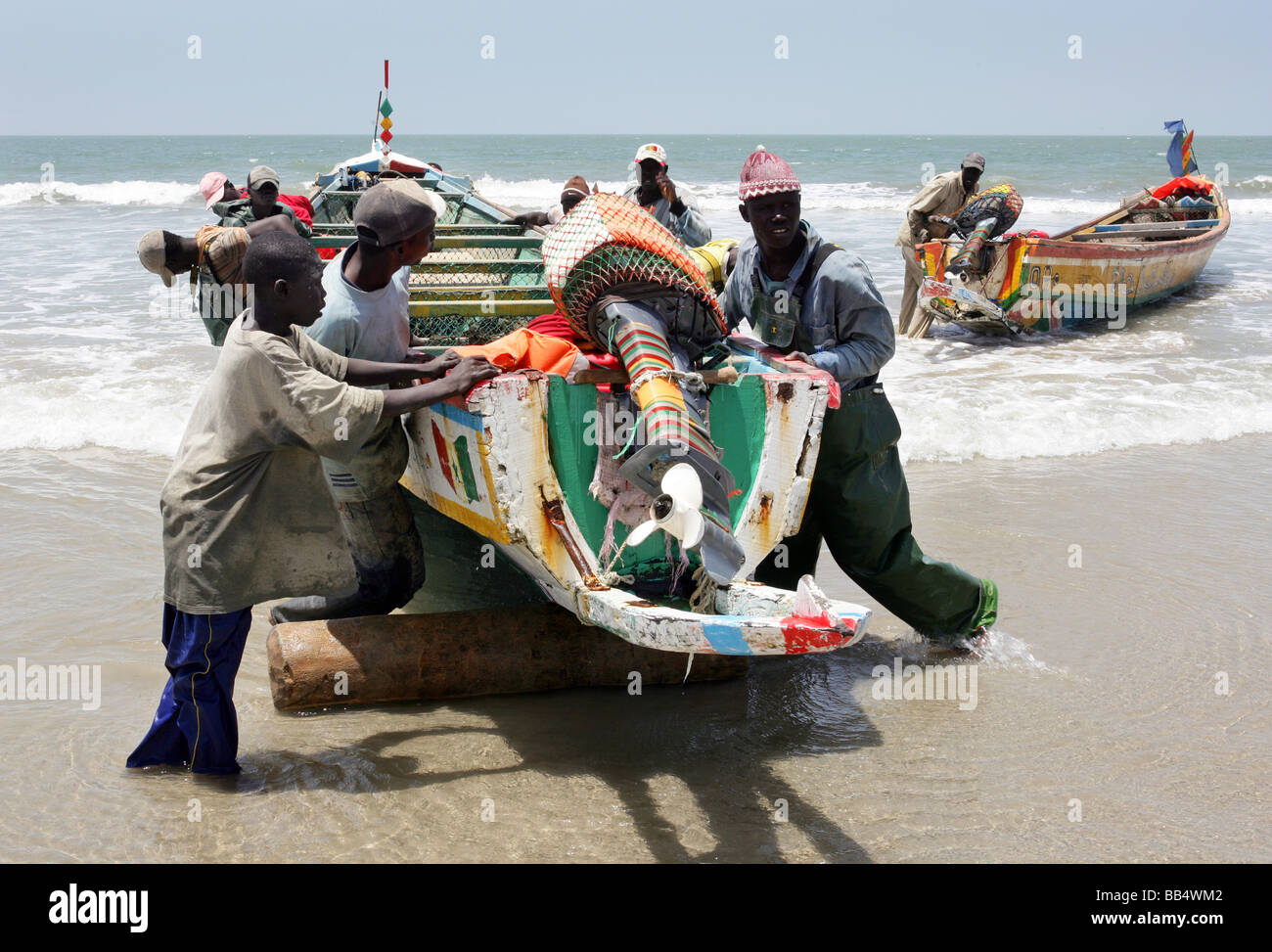 I pescatori di portare una barca fino sulla riva a Kap Skirring, Senegal Foto Stock