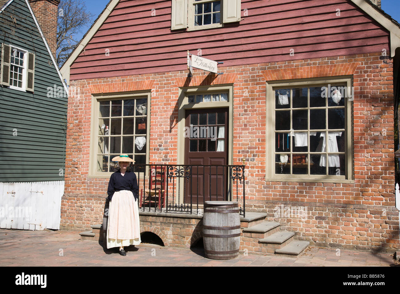 Una donna che accoglie i visitatori al Millinery (sartoria) negozio di Colonial Williamsburg, Virginia. Foto Stock