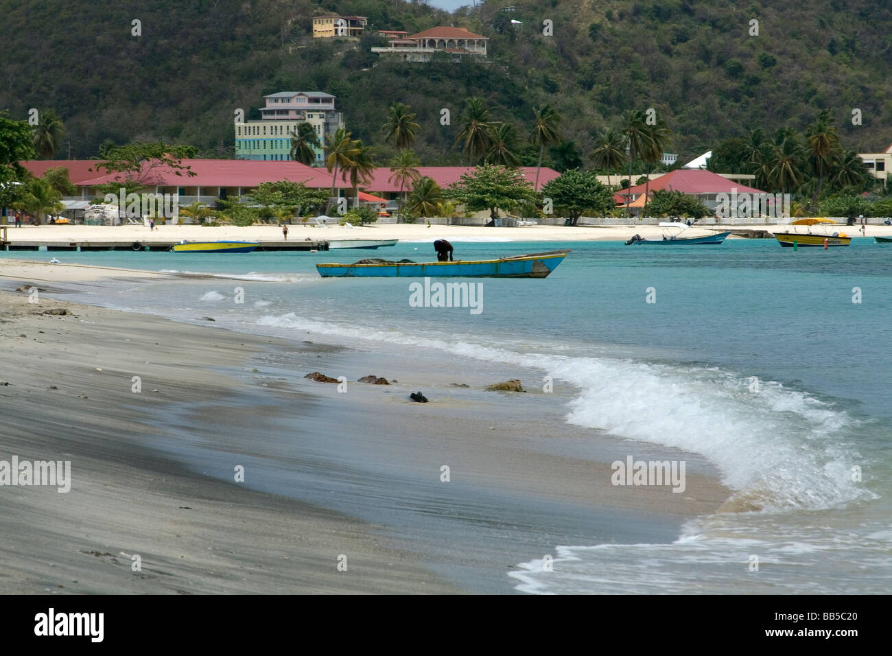 Vista di Grand Anse Beach con un pescatore di svuotare la sua barca da pesca di cattura recenti, Grenada, dei Caraibi. Foto Stock