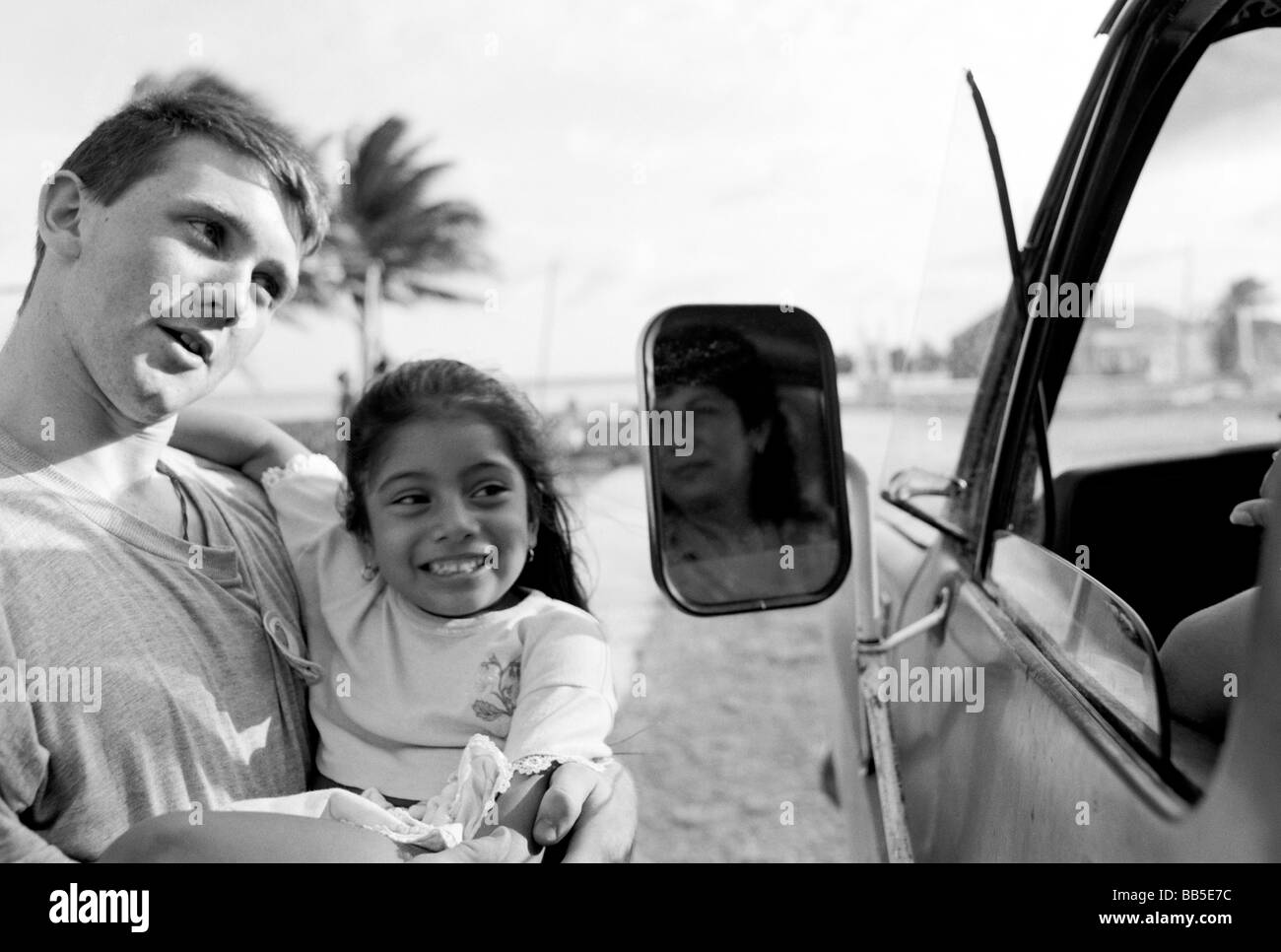 Western adulto holding ragazza locale e a parlare con le ragazze madre in auto Corozal, Belize, America Centrale Foto Stock