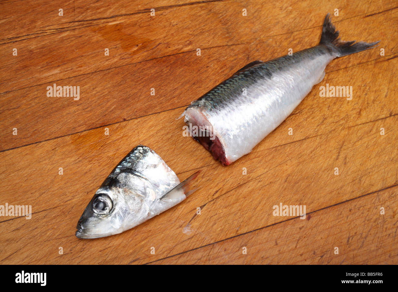 Aringa decapitato sul tagliere di legno Foto Stock