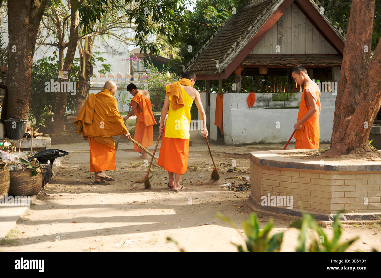 Il debuttante monaci spazzare i motivi del loro tempio a Luang Prabang, Laos Foto Stock