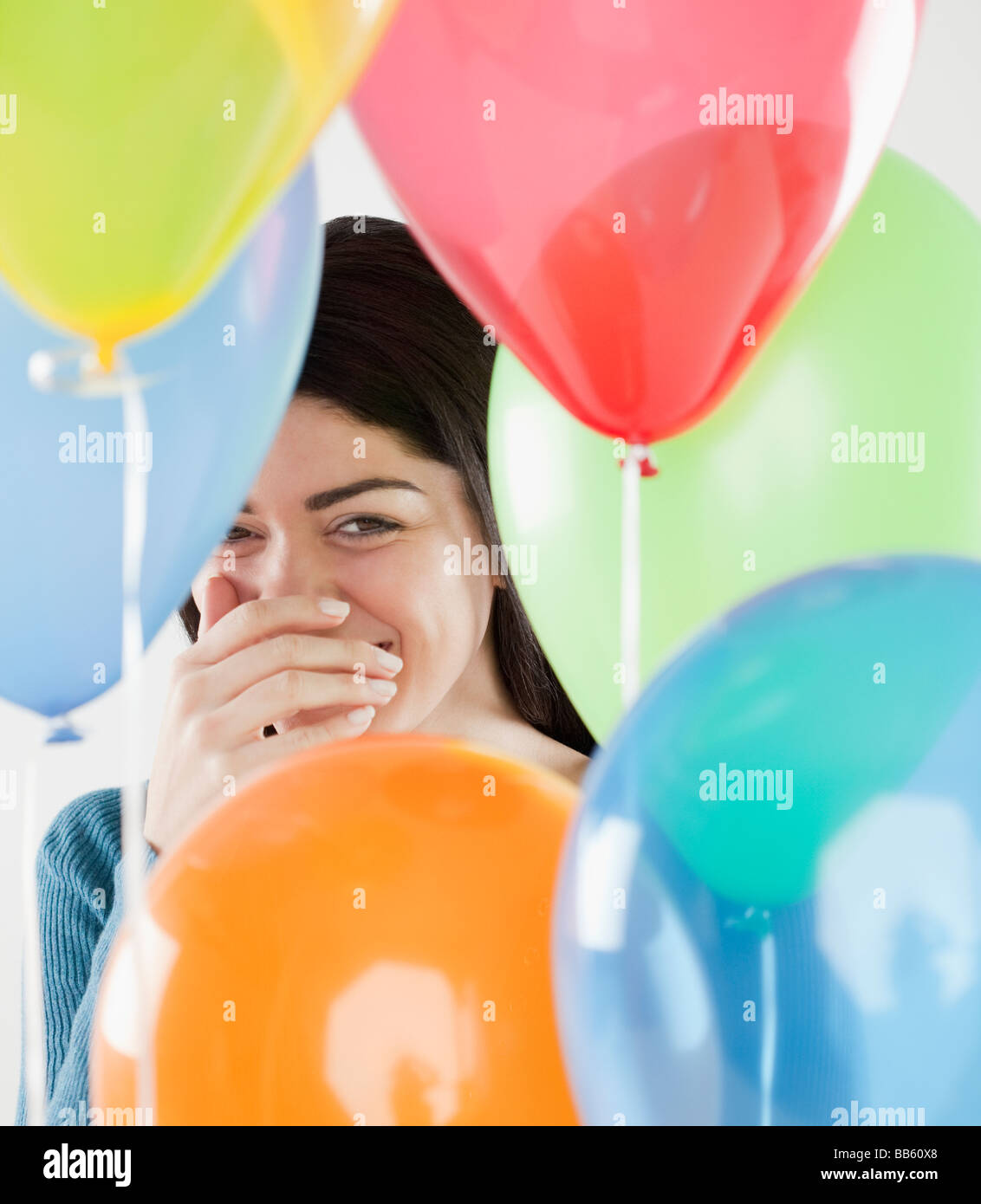 Donna ispanica ridendo dietro palloncini Foto Stock