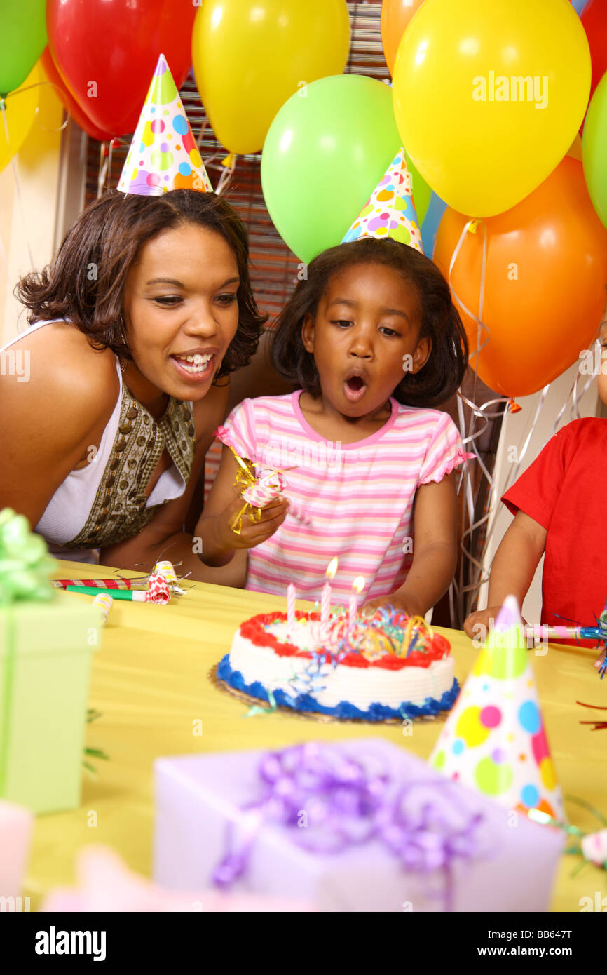 La madre e il giovane ragazza che spegne le candeline sulla torta del compleanno Foto Stock