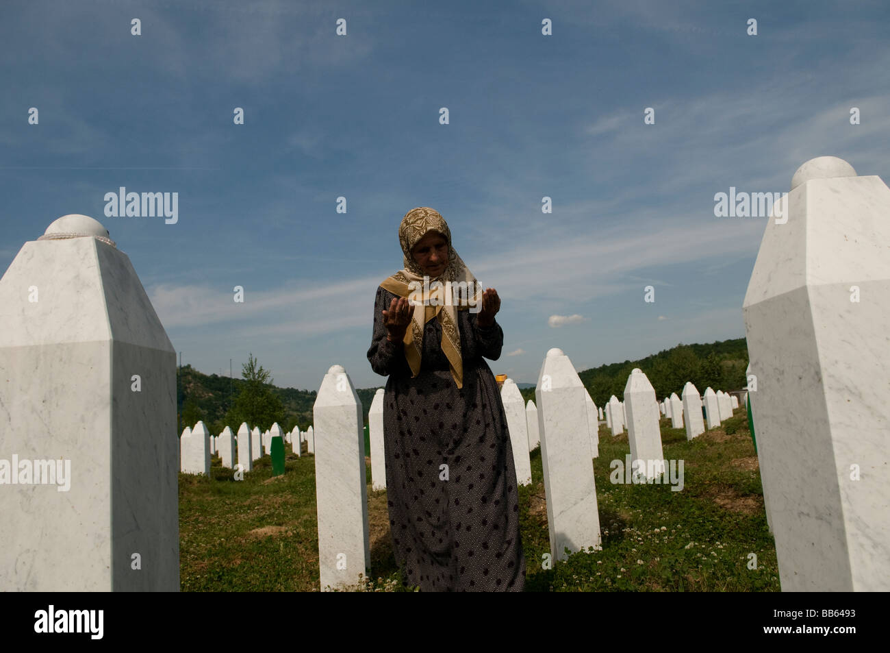 Una donna musulmana bosniaca prega tra le tombe dei suoi parenti, vittime del genocidio di Srebrenica, nel cimitero di Potocari vicino a Srebrenica, in Bosnia Foto Stock