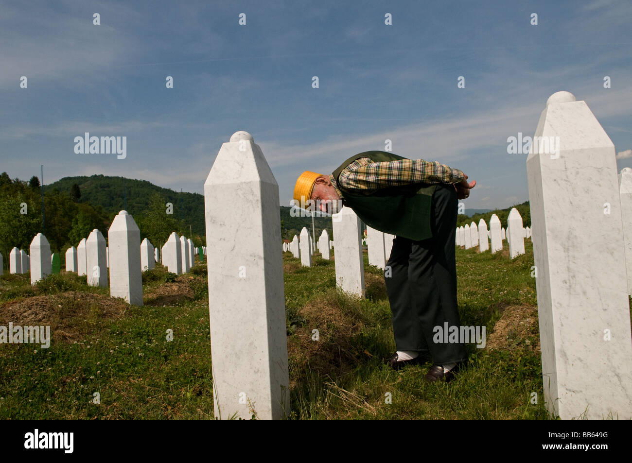 Un musulmano bosniaco si trova tra tombe dei suoi parenti, vittime del genocidio Srebrenica, nel cimitero di Potocari, vicino a Srebrenica, in Bosnia Foto Stock
