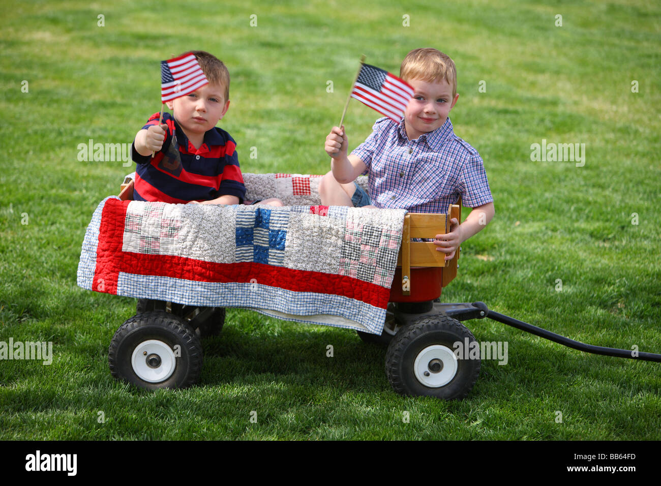 Due giovani ragazzi seduti in carro con bandierine americane Foto Stock