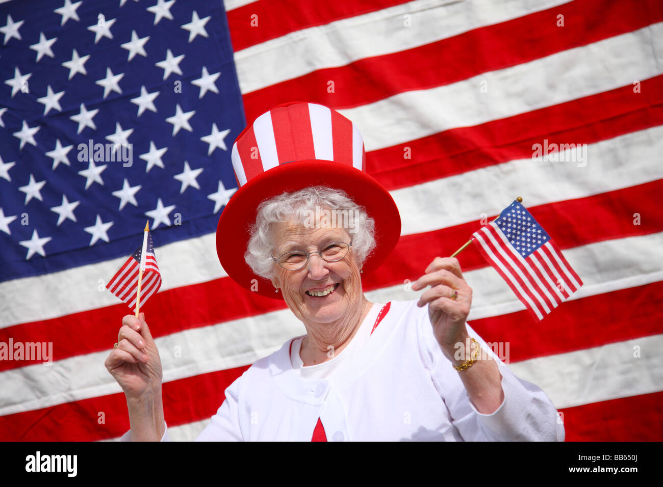 Senior patriottica donna sventolando bandiere e sorridente Foto Stock