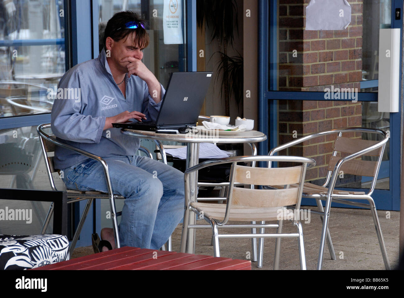 Uomo che lavora al computer portatile da soli al di fuori cafe Foto Stock