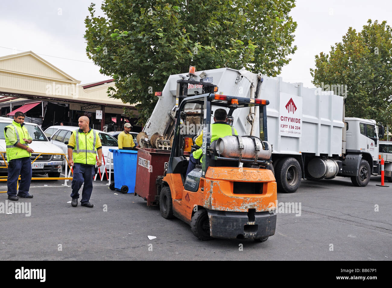 Uomini al lavoro per caricare i rifiuti su autocarro cittadine con il carrello elevatore a forche fuori mercato Queen Victoria Melbourne Australia Foto Stock