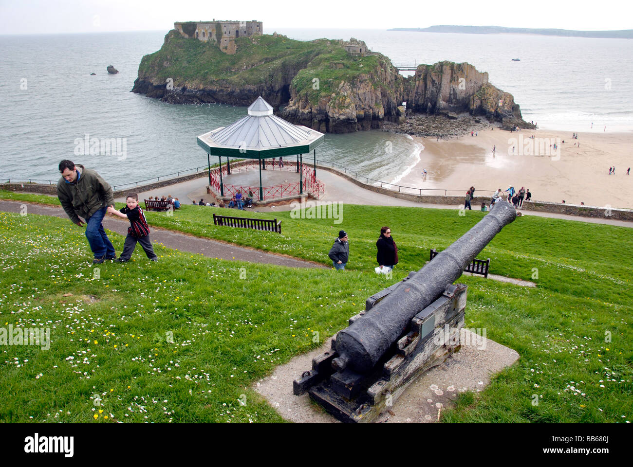 Affacciata sulla spiaggia in Tenby Galles con la vecchia canon sulla collina essendo salito il mio uomo & boy. vecchio bandstand & Isola in background Foto Stock