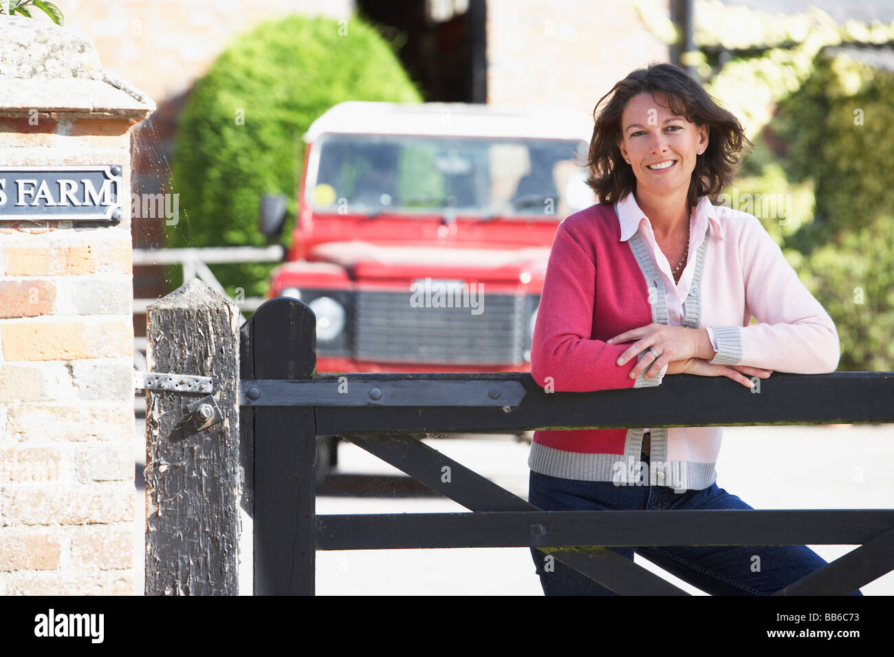 La moglie di un agricoltore che guarda sul Gate Farm Foto Stock