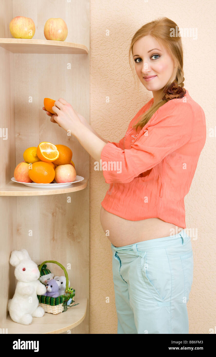 Incinta donna caucasica mangiare la frutta Foto Stock
