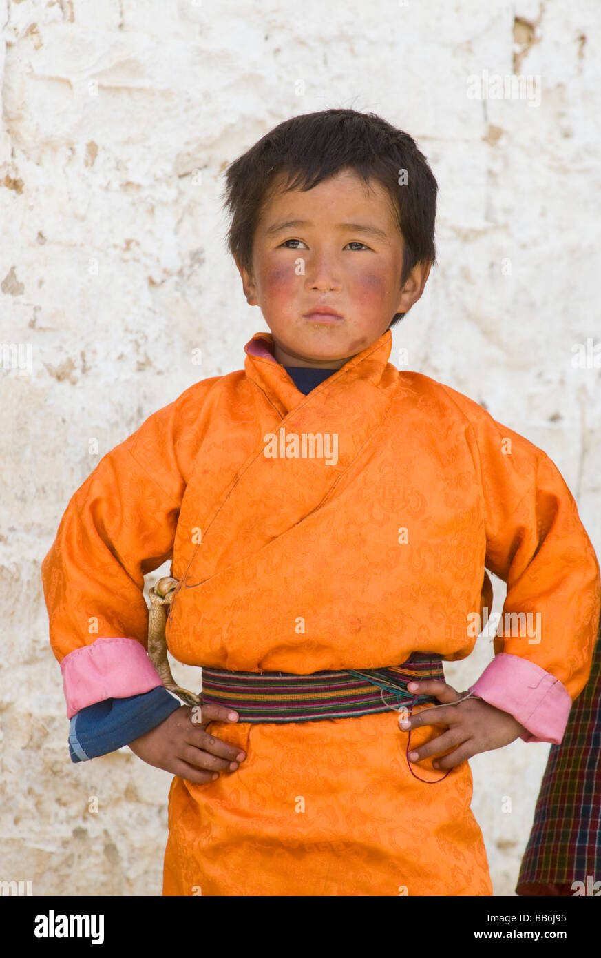 Giovane ragazzo indossa arancione 'gho' a tsechu o festival, Ura, Bumthang Valley, Bhutan Foto Stock